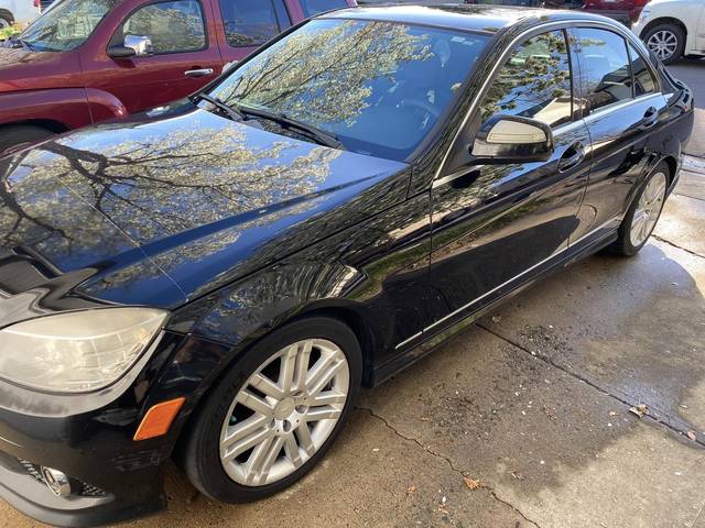 A black Mercedes sedan with trees reflected in the paint